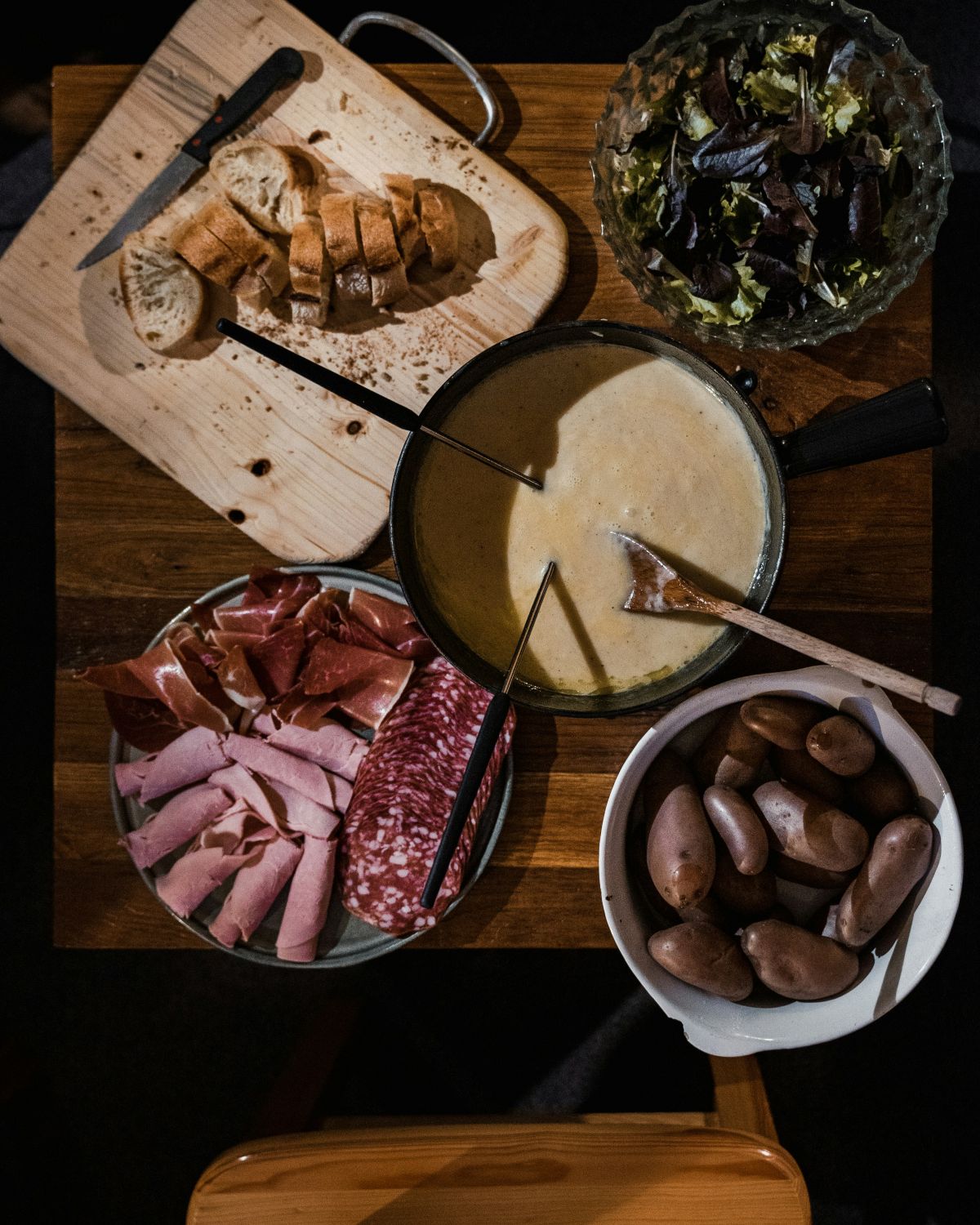 Overhead view of cheese fondue with cured meats